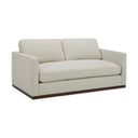 Three-quarters view of a Bobbi upholstered loveseat in a light beige or cream-colored fabric, with two loose back cushions, a single bench seat cushion, slim arms, and a dark, continuous wooden base.