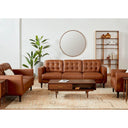 The Armando leather sofa and armchairs styled in a bright, mid-century modern living room with a round mirror, wood bookshelf, and a patterned rug.