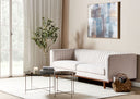 Modern living room with a light beige sofa, glass coffee table, and abstract wall art.