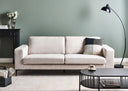 Light beige sofa in a living room with a black coffee table, lamp, and decorative items.