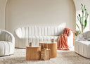 Modern living room with off-white sofa, wooden coffee tables, and decorative items.