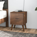 Wooden nightstand with two drawers next to a bed in a bedroom setting.