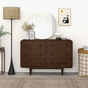 Wooden dresser with mirror, lamp, and decor items in a room setting.