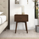 Wooden nightstand with a lamp and candle in a bedroom setting