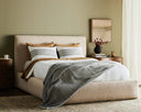 Neatly made bed with decorative pillows and a blanket in a bedroom setting.