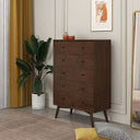 Wooden dresser in a room with a plant, mirror, and decor items.