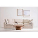 Sand colored sofa in a living room with a wooden coffee table and framed pictures on the wall.