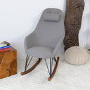Gray rocking chair in a room with wooden table and decorative items.