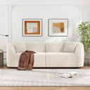 Off-white curved sofa in a living room with abstract art and a plant.