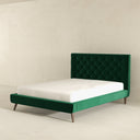 Green upholstered bed with tufted headboard on a beige background