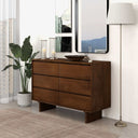 Wooden dresser in a room with decor elements like a plant, candles, and a lamp.