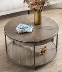 Round wooden coffee table with a vase of flowers and books on a wooden floor.