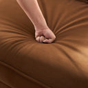 Hand pressing into a camel fabric sofa seat.