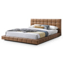 Tan leather bed with white bedding on a white background