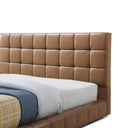 Tan tufted headboard with a bed partially visible on a white background