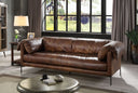 Mocha brown leather sofa in a living room with large windows and decor.