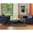Modern living room with dark blue leather sofas, a coffee table, and decorative elements.