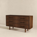Wooden dresser with four drawers on a beige background