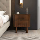 Wooden nightstand with two drawers next to a bed in a bedroom setting.