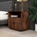 Wooden nightstand with books and lamp next to a bed in a bedroom setting
