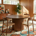Wooden dining table with chairs in a room with wooden walls and a colorful rug.