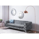 Gray tufted sofa in a room with decorative mirrors and a floor lamp.