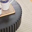 Black wooden side table with a decorative item on a beige carpet