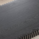 Close-up of a textured black cofee table top with a grid pattern on a beige rug in the background.