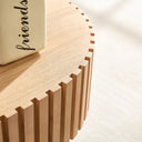 Close-up of a natural ash wooden coffee table with a 'friends' book on a light background.
