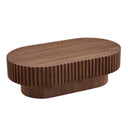Three-quarters view of a walnut oval wooden coffee table with ribbed surface on a white background.