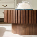 Close-up of the side ribbed part of a walnut oval coffee table in a minimalistic room.