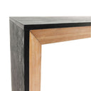 Close-up of a console table where a black surface meets a wooden surface on a white background.