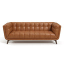 Adele 85-inch cognac top-grain leather sofa featuring a button-tufted backrest and inner arms, channel-tufted seat, and tapered dark wood legs, isolated on a white background.