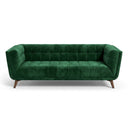 Adele 85-inch emerald green velvet sofa with button tufting and mid-century tapered wooden legs, isolated on a white background.