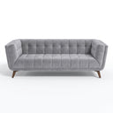 Adele 85-inch blue velvet sofa with button tufting on the back, channel-tufted seat cushions, and tapered dark wood legs, isolated on a white background.