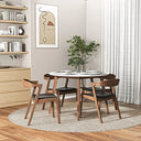 Modern dining room featuring the Adnan 43-inch round dining table with a white top and wooden legs, surrounded by four wooden chairs with black cushioned seats on a round woven rug.
