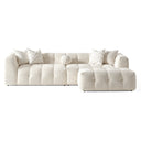 Agnes 113-inch ivory tufted chenille modular sofa with a matching modular ottoman, featuring low-profile channel-tufted seats, textured cream upholstery, chevron-patterned throw pillows, and a round accent pillow, isolated on a white background.