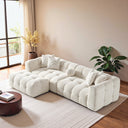 Agnes 113-inch ivory tufted chenille modular sofa with matching ottoman styled in a modern living room.