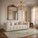 Agnes 90-inch tufted ivory chenille sofa styled in a luxurious Parisian-style living room with herringbone parquet floors, a large gold arched mirror, a distressed green area rug, and a crystal chandelier.