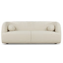 Alexis 84-inch modern low-profile sofa upholstered in textured ivory boucle fabric, featuring a curved backrest, thick integrated armrests, and two matching spherical throw pillows, shown against a plain white background.