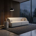 Modern Alexis 84-inch ivory boucle sofa with round pillows in a living room featuring a black arc floor lamp, stone side table, wood slat wall, and a large window overlooking a foggy forest.