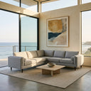 Allegra 105-inch light grey fabric sectional corner sofa with bolster pillows in a modern living room featuring an ocean view, low stone coffee table, and abstract wall art.