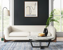The Amala sofa styled in a modern living room with a dark accent wall, abstract art, and a marble coffee table, showcasing its organic design.
