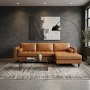 Anita 102-inch tan genuine top-grain leather right-facing sectional sofa with tufted seating and bolster pillows styled in a modern living room setup.