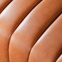 Close-up of the cognac genuine leather upholstery on the April 86-inch sofa, highlighting the channel tufting and natural leather grain texture.
