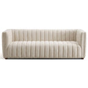 April 86-inch mid-century modern channel-tufted sofa upholstered in textured beige bouclé fabric, featuring vertical channeling across the seat, back, and arms, with small wooden legs, set against a plain white background.