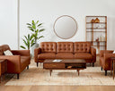 The Armando leather sofa and armchairs styled in a bright, mid-century modern living room with a round mirror, wood bookshelf, and a patterned rug.