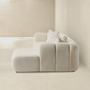 Side view of the Bella 114-inch ivory tufted bouclé right-facing sectional sofa featuring vertical channel cushioning, rounded armrests, matching chevron throw pillows, and a right-side chaise lounge against an ivory studio background.