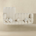 Top view of the Bella 114-inch ivory tufted bouclé right-facing sectional sofa featuring vertical channel cushioning, rounded armrests, matching chevron throw pillows, and a right-side chaise lounge against an ivory studio background.