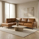 Carla 109-inch tan genuine leather left-facing sectional sofa with tapered wooden legs styled in a modern living room with a travertine coffee table and textured area rug.